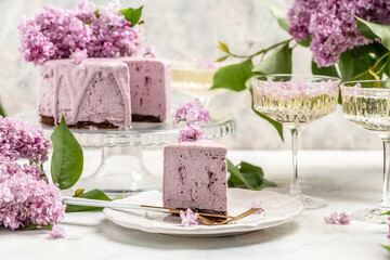 Obraz na płótnie Canvas Delicious dessert blueberry tart with fresh berries, sweet tasty mousse cake, berry pie with a bouquet of purple blooming lilacs, French cuisine