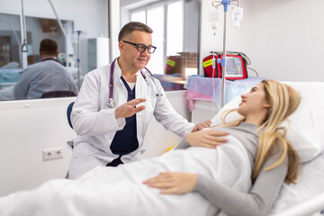 Obraz premium Mature Doctor taking care of patient in hospital room