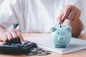 Save money, Woman hand putting coins into blue piggy bank for account save money, Calculate saving...