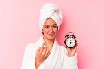 Young venezuelan woman late for work isolated on pink background pointing with finger at you as if...