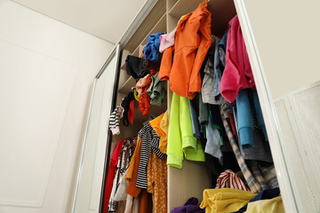 Messy wardrobe with different clothes indoors, low angle view. Fast fashion concept