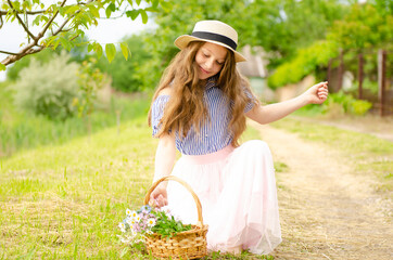 Girl with a basket of flowers sitting on the grass