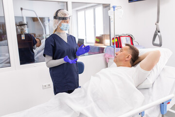 Obraz premium Doctor wearing PPE suit and Surgical mask and Checking infected patient in quarantine room Covid-19. Coronavirus outbreak or Covid-19, Concept of Covid-19 quarantine