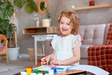 a little cute girl paints with paints at home