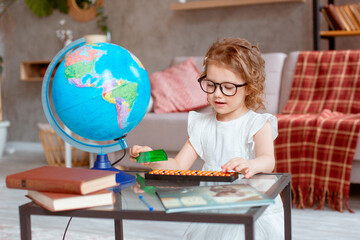 little schoolgirl girl with glasses is engaged at home