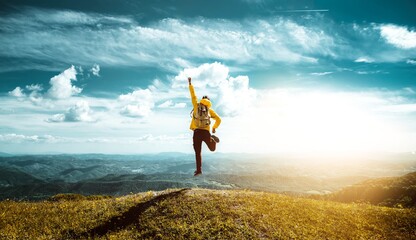 Hiker with backpack raising hands jumping on the top of a mountain - Successful man with arms up...