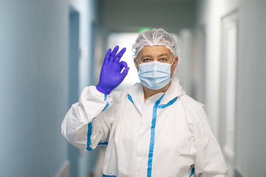 Hospital covid-19 treatment concept. Cheerful doctor in white scrubs, gloves, medical mask, okay sign, give permition, consult patient, approve safety measures during coronavirus