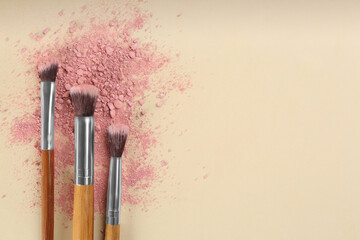 Fototapeta premium Makeup brushes and scattered eye shadow on beige background, flat lay. Space for text