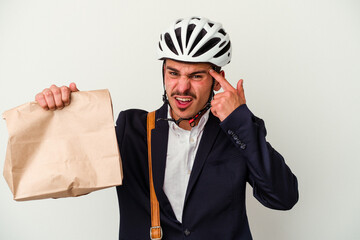 Young business caucasian man wearing bike helmet and holding take way food isolated on white background showing a disappointment gesture with forefinger.