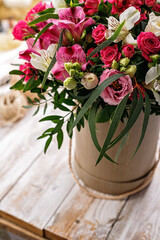 Gift bouquet of flowers to a cardboard box. Pink rose and alstrameria in a round gift box on a wooden background. Close-up. Vertical shot. Copy space.