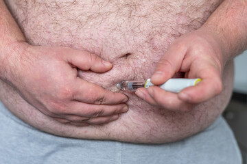 close up of fat man hands making injection with insulin pen or syringe, medicine, diabetes, glycemia, health care and people concept.