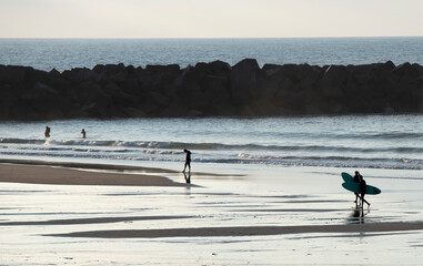 Fototapeta na wymiar surfers on the beach at sunset