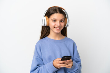 Little girl over isolated white background listening music with a mobile and looking front