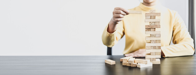 Businesswoman playing with wooden blocks, comparing business management concepts on risk, planning...