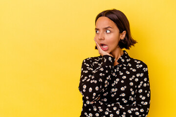 Young mixed race woman isolated on yellow background being shocked because of something she has seen.