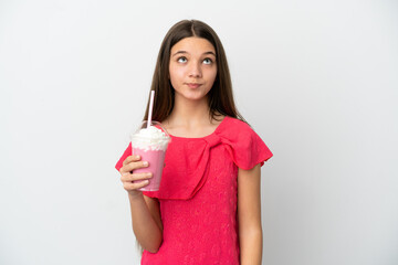 Little girl with strawberry milkshake over isolated white background and looking up