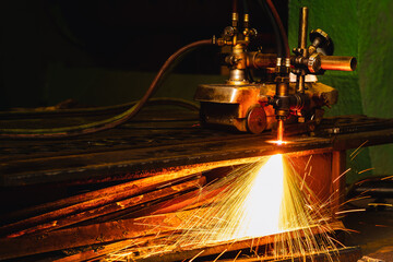 Acetylene torch semi auto machine cutting metalwork fabrication with bright sparks in factory.