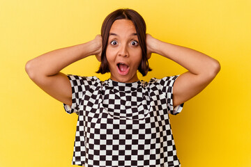 Young mixed race woman isolated on yellow background covering ears with hands trying not to hear too loud sound.