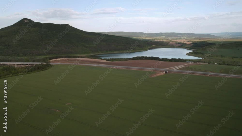 Wall mural drone flight over beautiful nature with green rolling fields and a newly built highway that passes t