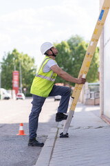 telecommunication technician working at height with ladder and safety helmet