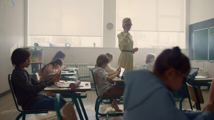 Female teacher and students with digital tablets having lesson in classroom - Powered by Adobe