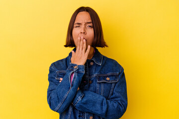 Young mixed race woman isolated on yellow background yawning showing a tired gesture covering mouth with hand.