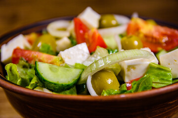 Ceramic plate with greek salad on wooden table