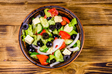 Ceramic plate with greek salad on wooden table. Top view