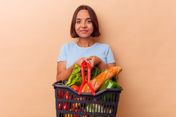 Fototapeta na wymiar Young mixed race woman doing the shopping isolated on beige background