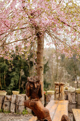 Wooden carved statue of owl, cherry blossom tree on sunny spring day, landscape park near castle Kost or Bone, Wood idol, Bohemian Paradise or Cesky Raj, Czech Republic