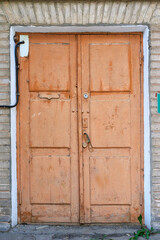 An old brown wooden door on the stone wall.
