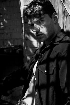 Portrait of handsome serious young man looking at camera with open black shirt revealing muscular pecs and sixpack abs