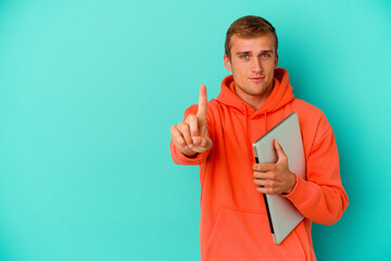 Young student caucasian man holding a laptop isolated on blue background