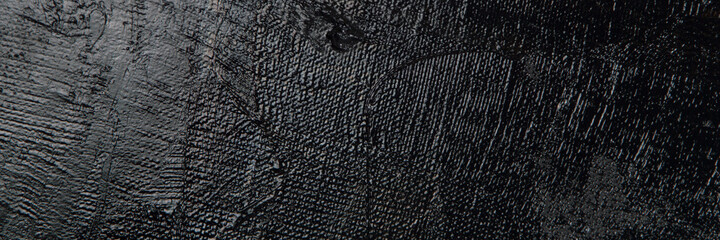 Dark creative background - rough linen canvas unevenly covered with black primer, reflections of light. Toning, blurring, selective focus.
