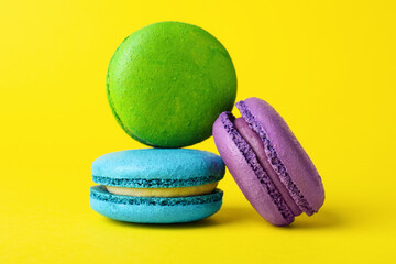 Delicious colorful macarons on yellow background, closeup