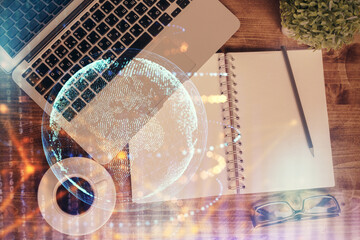 Double exposure of map hologram drawing over study table background with computer. Concept of international network. Top view.