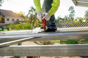 Construction worker install new roof,Roofing tools,Electric drill used on new roofs with Metal Sheet.