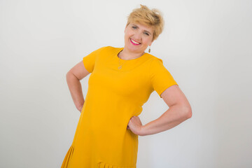 Obraz premium Ładna, elegancka kobieta w średnim wieku w żółtej sukience.