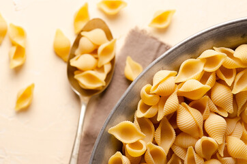 Abissine rigate pasta in a spoon and in a metal container with a beige napkin, on a light...