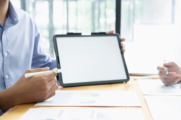 Handsome young businessman working with digital tablet while standing in front of the big window in office
