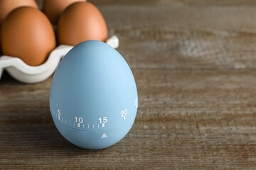Kitchen timer and eggs on wooden table. Space for text