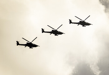Three helicopters in flight. Military helicopters. Cloudy sky in the background.