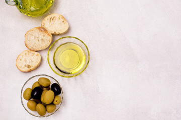 Glass Bowls with Olive Oil Slice of Bread and Green Olives on Light Gray Background Top View Copy Space