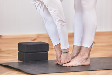 Closed portrait with no visible face of Forward Bend Yoga pose. yoga mat and smooth background