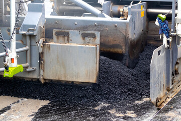Fototapeta premium Asphalt paver on the road while laying asphalt, part of the car close up. Road repair. Laying a new road