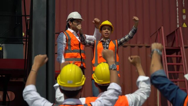 harbor Workers protest in Cargo freight ship for import export logistic over container box warehouse . Group of protestors shouting get out and  fists raised up . woman  Strike of labor in industry