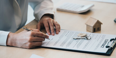 close-up view hands of businesswoman signing leasing home documents and have a apartment keys on paperwork