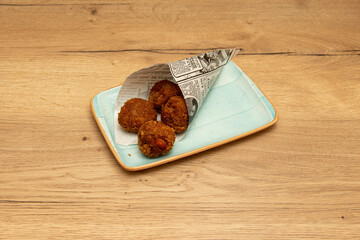 Newspaper cornet with a portion of round croquettes stuffed with ham