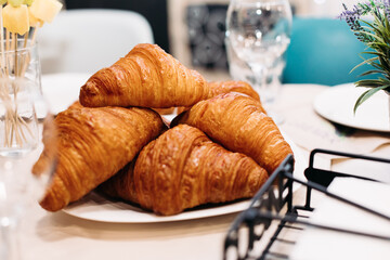 Tasty crisp croissants on a white plate sitting on table
