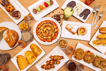 Top view image of desserts, pasta, sweets, breads, muffins, palm trees, juices and typical condiments of a patisserie